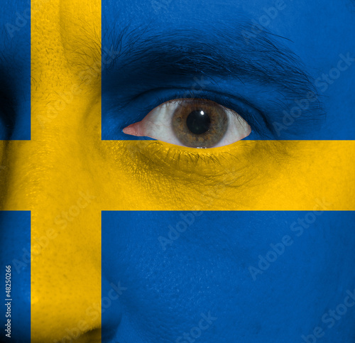 Photo: face with the Swedish flag painted on it face with the Swedish flag painted on it