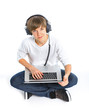 Photo: Boy wearing headphones sitting with a laptop Boy wearing headphones sitting with a laptop