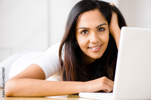 Photo: Beautiful Indian woman student using laptop computer at home Beautiful Indian woman student using laptop computer at home