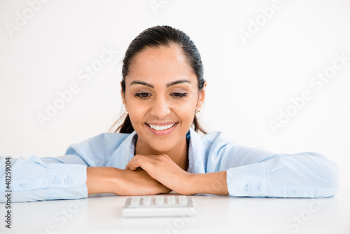 Photo: Happy Indian business woman using calculator Happy Indian business woman using calculator