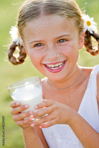Photo: Healthy kid - lovely girl drinking fresh milk outdoors Healthy kid - lovely girl drinking fresh milk outdoors