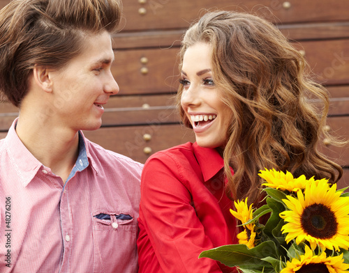 Photo: Loving young man hugging his girlfriend with sunflowers in their Loving young man hugging his girlfriend with sunflowers in their