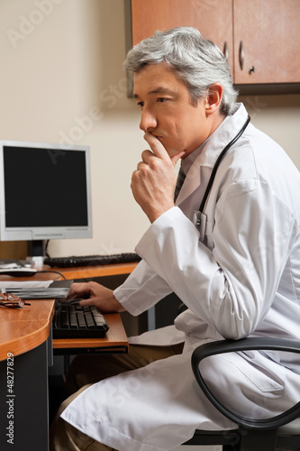 Photo: Pensive Doctor Sitting At Desk Pensive Doctor Sitting At Desk
