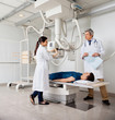 Radiologists With Patient In X-ray Room