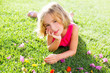 blond kid girl lying relaxed in garden grass with flowers