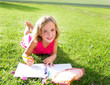child kid girl doing homework smiling happy on grass