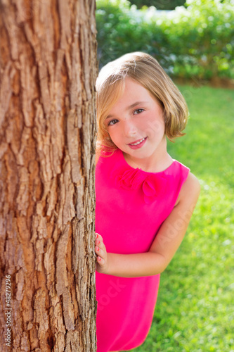 Photo: child happy girl smiling rear tree trunk in garden child happy girl smiling rear tree trunk in garden