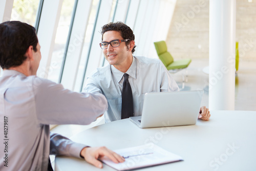 Photo: Two Businessmen Having Meeting Around Table In Modern Office Two Businessmen Having Meeting Around Table In Modern Office
