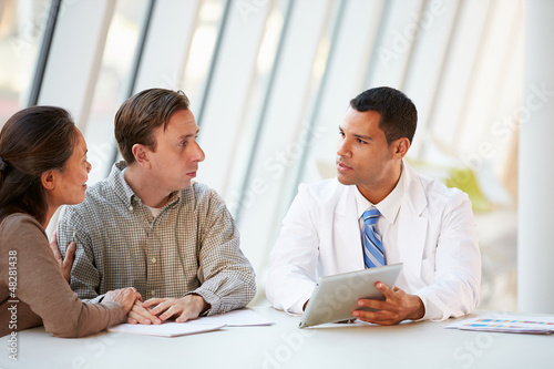 Photo: Doctor Using Tablet Computer Discussing Treatment With Patients Doctor Using Tablet Computer Discussing Treatment With Patients