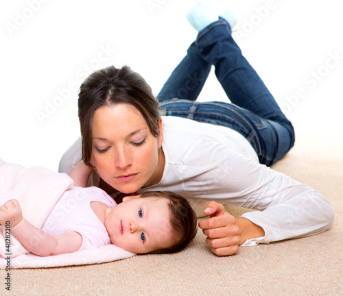 Photo: Baby and mother lying on beige carpet together Baby and mother lying on beige carpet together