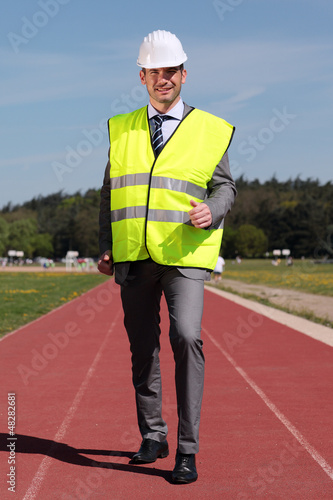 Photo: businessman with hard hat and yellow vest on track businessman with hard hat and yellow vest on track