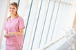 Nurse Using Digital Tablet In Corridor Of Modern Hospital