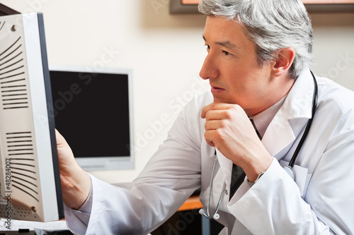 Photo: Doctor Looking At Computer Screen Doctor Looking At Computer Screen