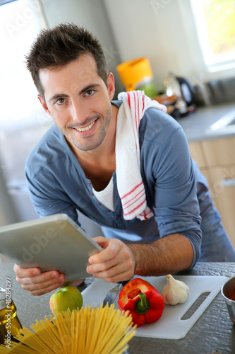 Photo: Closeup of smiling man in kitchen using tablet Closeup of smiling man in kitchen using tablet
