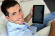 Man sitting in sofa using electronic tablet