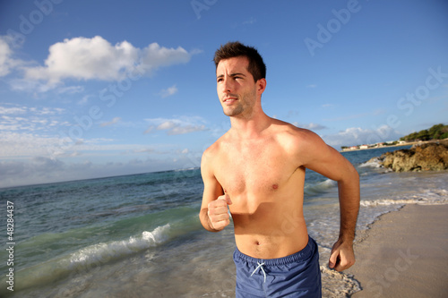 Photo: Young man running on the beach Young man running on the beach