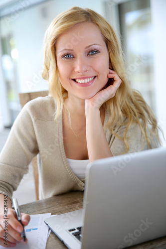 Photo: Smiling woman working from home on laptop Smiling woman working from home on laptop