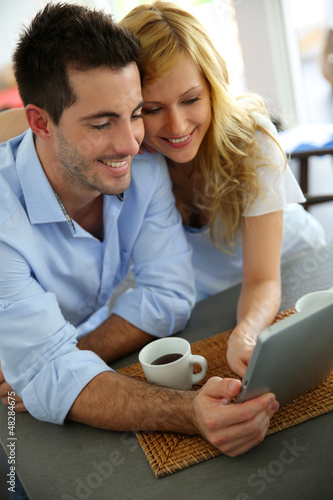 Photo: Young couple websurfing with tablet in home kitchen Young couple websurfing with tablet in home kitchen