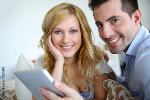 Photo: Cheerful couple websurfing with digital tablet at home Cheerful couple websurfing with digital tablet at home