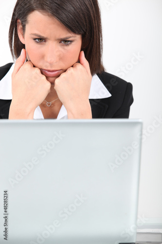 Photo: young businesswoman looking worried in front of laptop young businesswoman looking worried in front of laptop