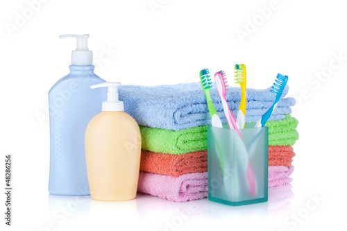 Photo: Four colorful toothbrushes, cosmetics bottles and towels Four colorful toothbrushes, cosmetics bottles and towels