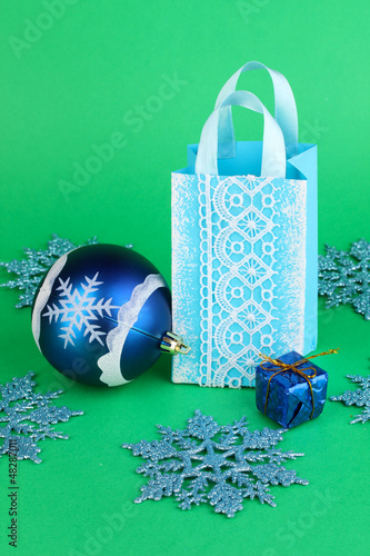Photo: Christmas paper bag for gifts on green background Christmas paper bag for gifts on green background