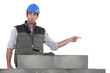 Shocked builder stood by wall pointing