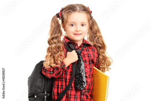 Photo: A little girl standing with backpack and book A little girl standing with backpack and book