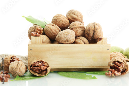 Photo: walnuts with green leaves in woooden crate, isolated on white walnuts with green leaves in woooden crate, isolated on white