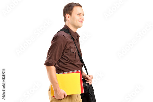 Photo: A male student with shoulder bag holding books and walking A male student with shoulder bag holding books and walking
