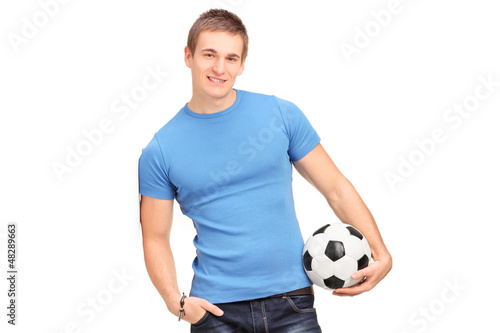 Photo: A young man leaning on a wall and holding a soccer ball A young man leaning on a wall and holding a soccer ball