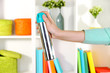 Sprayed air freshener in hand on white shelves background