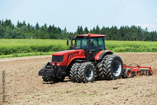 Photo: Ploughing tractor at field cultivation work Ploughing tractor at field cultivation work