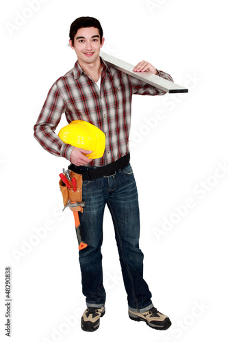 Photo: Young builder carrying a plank of wood Young builder carrying a plank of wood