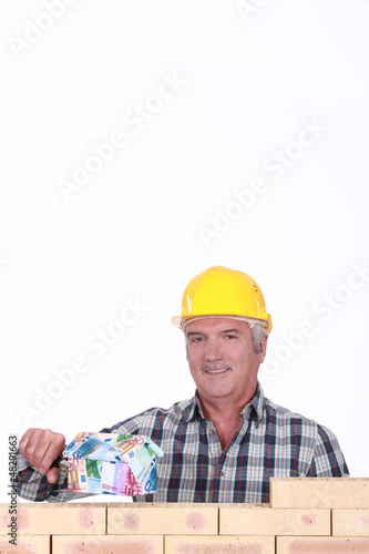 Photo: Builder with a house made of money Builder with a house made of money