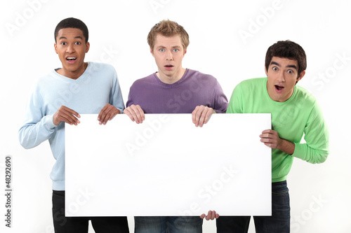 Photo: Three surprised men holding poster Three surprised men holding poster