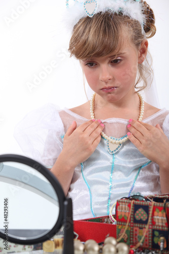 Photo: Girl dressed as a princess trying on necklace Girl dressed as a princess trying on necklace