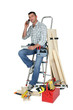 Laborer with phone and laptop sitting on a ladder