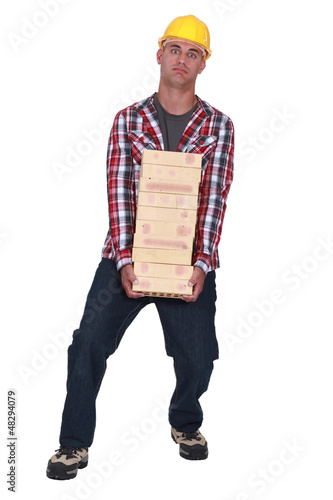 Photo: Tradesman carrying a heavy load of bricks Tradesman carrying a heavy load of bricks