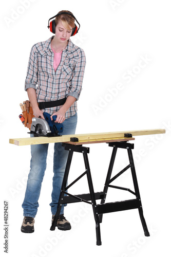 Photo: Woman using a circular saw to cut a wooden plank Woman using a circular saw to cut a wooden plank