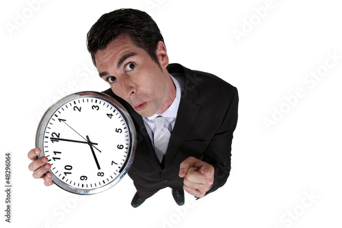 Photo: High-angle shot of a businessman holding a clock High-angle shot of a businessman holding a clock