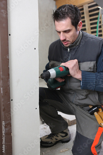 Photo: Man drilling an interior wall Man drilling an interior wall