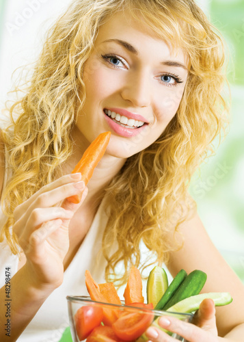 Photo: Young woman eating vegetables Young woman eating vegetables