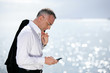 Businessman sending a text message by the seaside