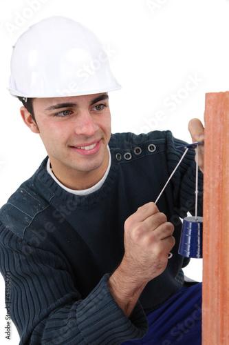 Photo: Worker checking wall is straight Worker checking wall is straight