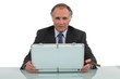 A businessman looking in a briefcase and smoking a cigar.