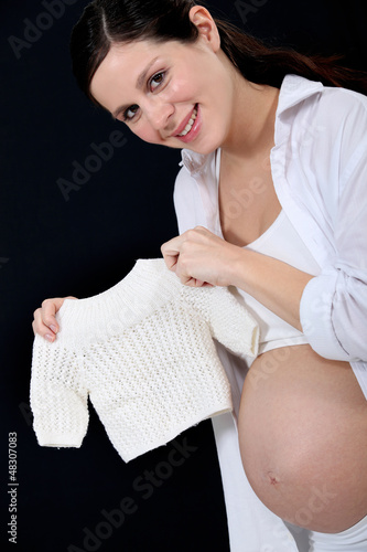 Photo: portrait of beautiful pregnant woman holding handknit pullover portrait of beautiful pregnant woman holding handknit pullover