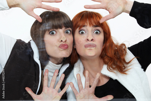 Photo: Two women pressing their faces against glass Two women pressing their faces against glass