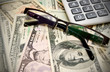 Glasses and calculator on dollars