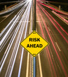 "RISK AHEAD" sign against highway trails